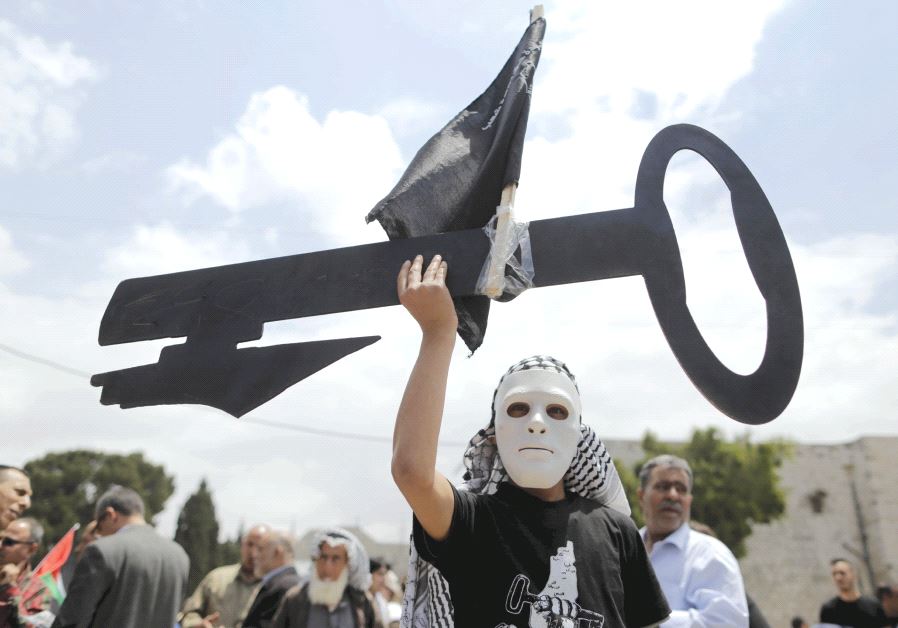 A Palestinian wearing a mask holds a cut-out of a key during a rally ahead of the ‘Nakba Day’ in Bethlehem in 2015 (photo credit: REUTERS)
