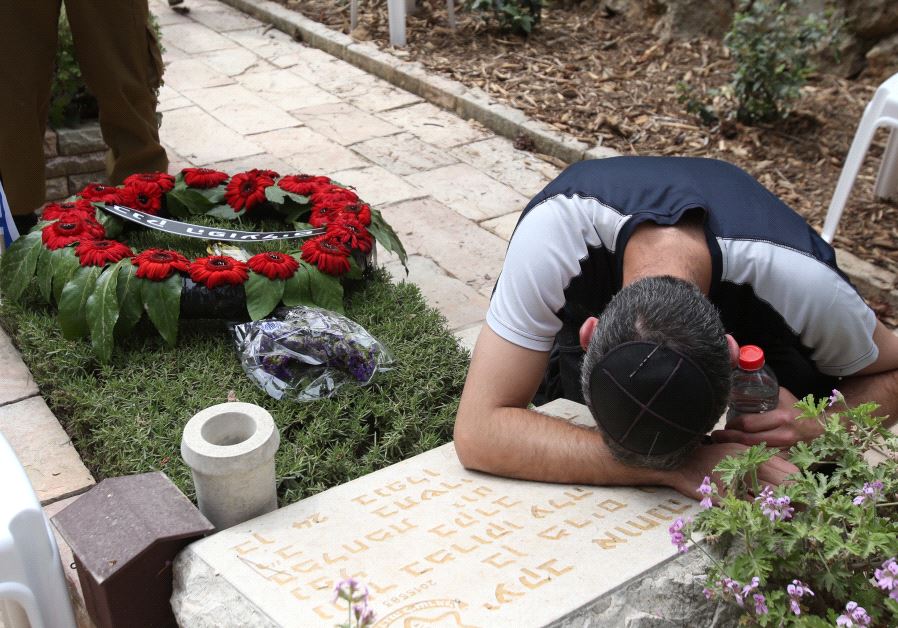 A man mourns over a gravestone at the national military cemetery on Mount Herzl in Jerusalem on Memorial Day, May 1, 2017 (MARC ISRAEL SELLEM) 