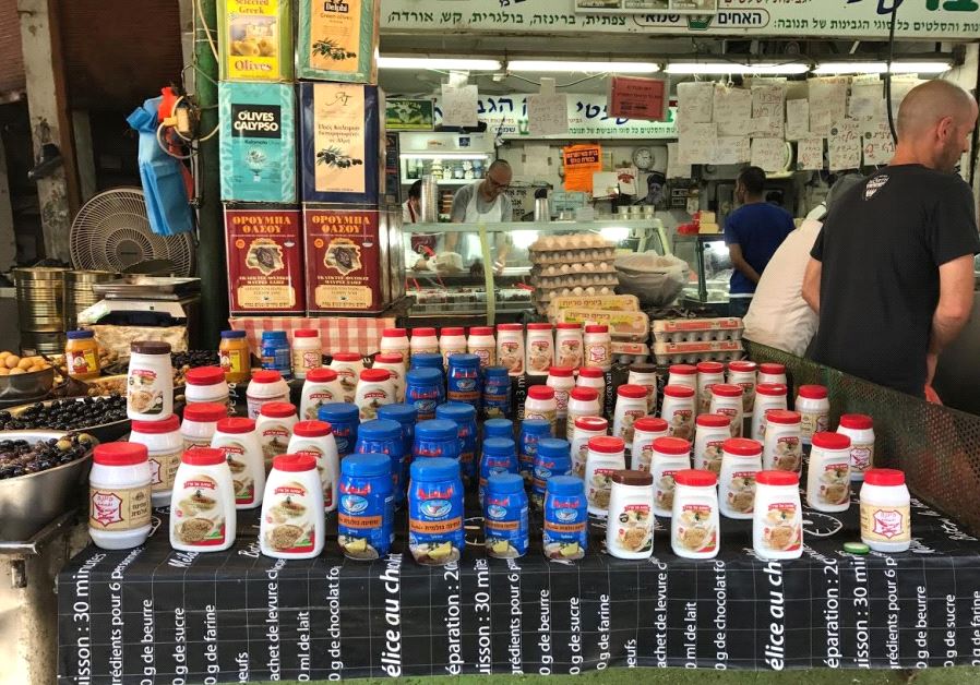 Karawan tahini (the blue jar) being sold alongside Al Arz tahini from Nazareth, and Yona tahini from Nablus at Tel Aviv's Carmel Market, May 19, 2017 (photo credit: ELIYAHU KAMISHER)