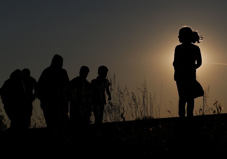 Migrants walk along rail tracks on sunset close to a migrant collection point in Roszke, Hungary