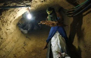 A Palestinian transports goods in a tunnel.