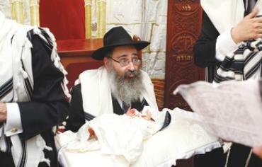 Rabbi holds boy for circumcision