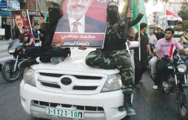 HAMAS GUNMEN hold a poster depicting Mohamed Morsi of the Muslim Brotherhood in Gaza City June 2012.