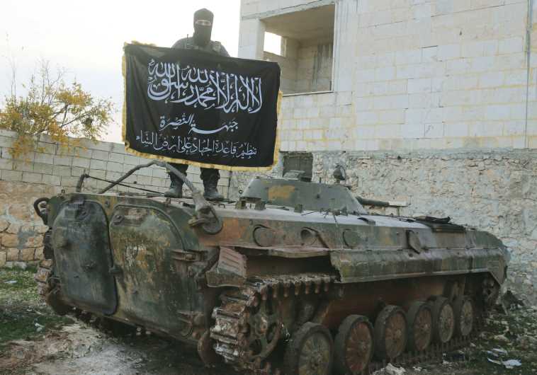 A member of al-Qaida’s Nusra Front fighting with other Sunni Islamists in support of the Syrian opposition pose on a tank near Aleppo in November 2014. (credit: REUTERS)