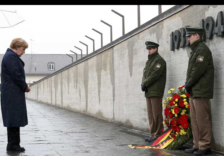 German Chancellor Merkel observes a moment of silence as she lays a wreath during a ceremony at the memorial in the former German Nazi concentration camp in Dachau. (credit: REUTERS)