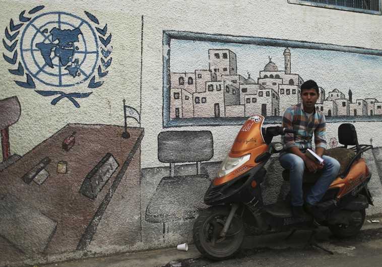 A Palestinian student sits on a motorcycle as he watches a protest at the gate of the headquarters of UNRWA in Gaza City (credit: REUTERS)