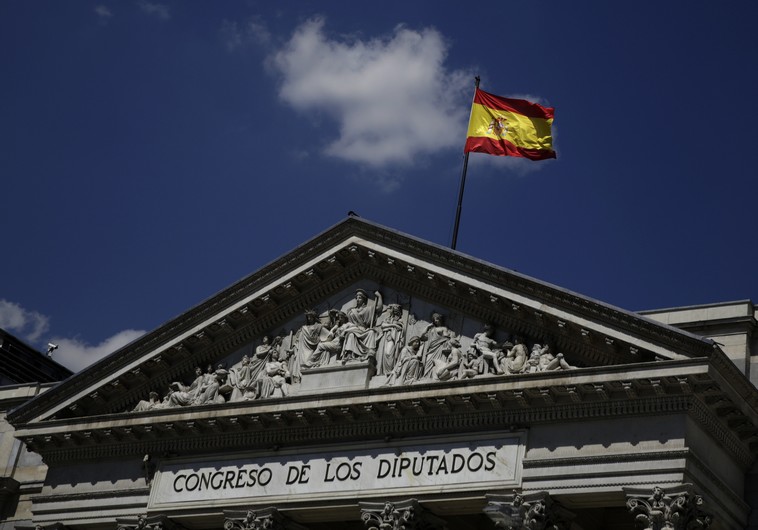 A Spanish flag waves over the Spanish parliament in Madrid (credit: REUTERS)