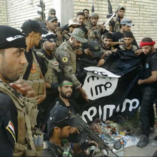 Iraqi security forces hold an Islamist State flag which they pulled down at the University of Anbar, in the western city of Ramadi on Sunday. (credit: REUTERS)