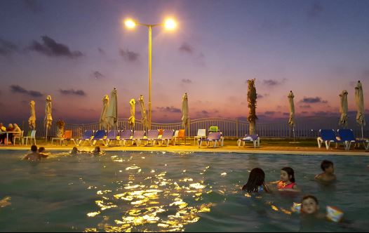 Palestinian children swim in a pool as they enjoy the warm weather with their families at the Blue Beach Resort in Gaza