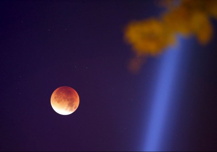 The Moon, appearing in a dim red color, is covered by the Earth's shadow during a total lunar eclipse over Paris (credit: REUTERS)