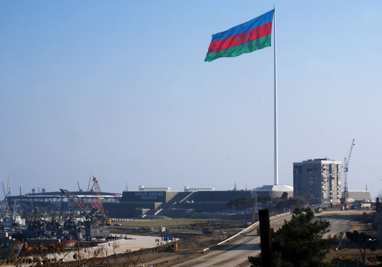 An enormous Azerbaijani flag flies above the construction site of a landmark concert hall on the Caspian Sea shoreline in Baku