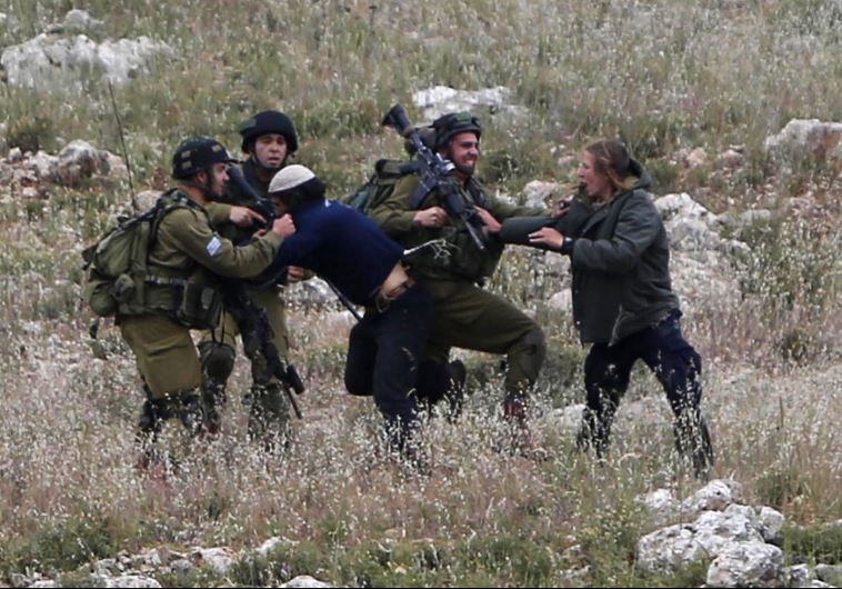 Israeli soldiers detain Jewish settlers during clashes with Palestinians near the West Bank village of Deir Jarir, near Ramallah (credit: REUTERS)