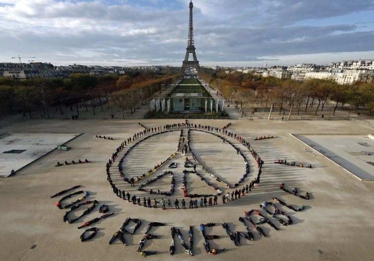 Hundreds of environmentalists arrange their bodies to form a message of hope and peace in front of the Eiffel Tower as the World Climate Change Conference 2015 convened at Le Bourget near the French capital (credit: REUTERS)