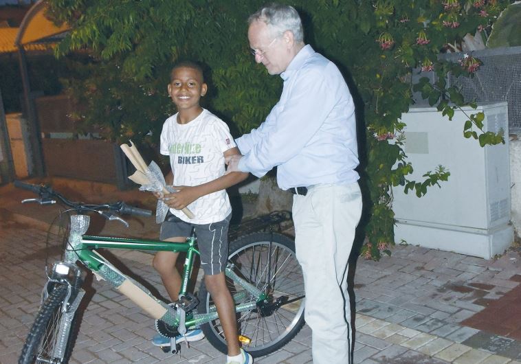 ONEFAMILY founder and chairman Marc Belzberg presents a bicycle yesterday to a son of slain taxi driver Amin Shaaban. (credit: SARAH LEVIN)