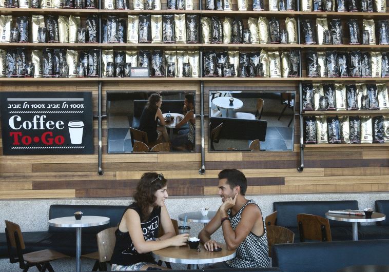 A couple relax at a branch of Aroma in Tel Aviv, one of Israel’s most successful coffee chains (credit: MARC ISRAEL SELLEM)