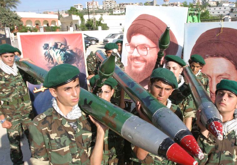 Hezbollah members carry mock rockets next to a poster of the group's leader Sayyed Hassan Nasrallah [FIle] (credit: REUTERS)