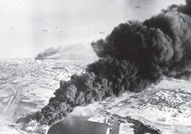 Smoke rises from oil tanks beside the Suez Canal hit during the initial Anglo-French assault on Port Said in November 1956 (credit: Wikimedia Commons)