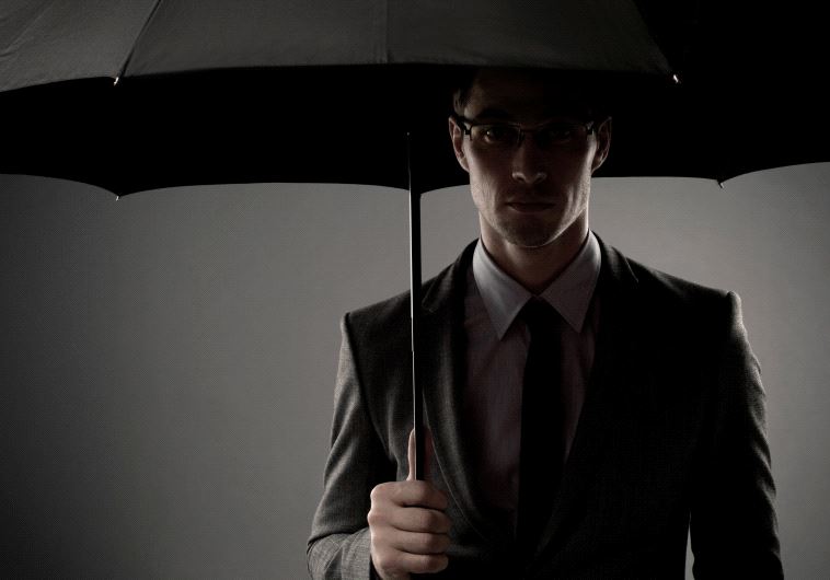 Un homme mystérieux en costume noir debout dans l'ombre sous un parapluie, ressemblant à un espion ou à un agent secret [Illustration] (crédit : INGIMAGE)