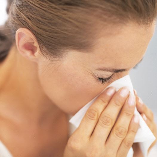 A woman blowing her nose into a tissue, possibly after or sneeze or while sick (credit: INGIMAGE)