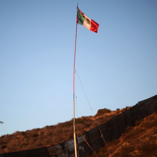 A Mexican flag is seen next to a section of the wall separating Mexico and the United States, in Tijuana, Mexico, October 6, 2016 (credit: REUTERS)