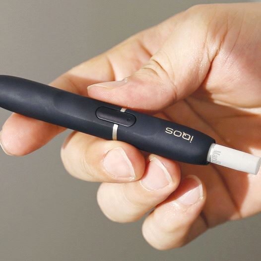 A CUSTOMER holds a Philip Morris iQOS e-cigarette at an iQOS store in Tokyo last year (credit: REUTERS)