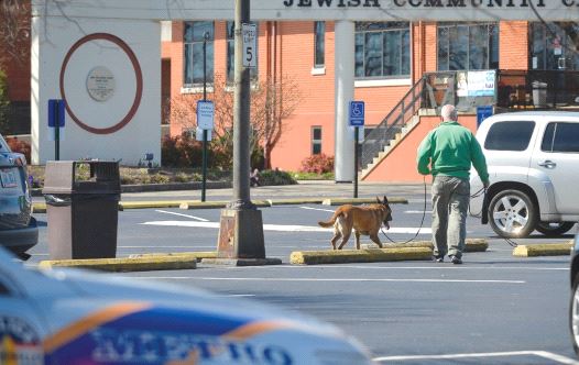 A policeman and a detection dog search for explosives after a bomb threat to the Jewish Community Center in Louisville, Kentucky