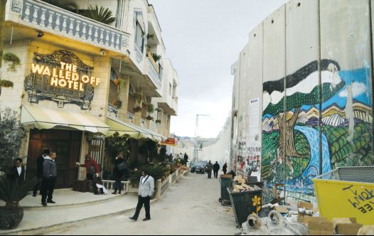 People stand outside the Walled Off Hotel, which was opened by street artist Banksy, in Bethlehem (credit: REUTERS)