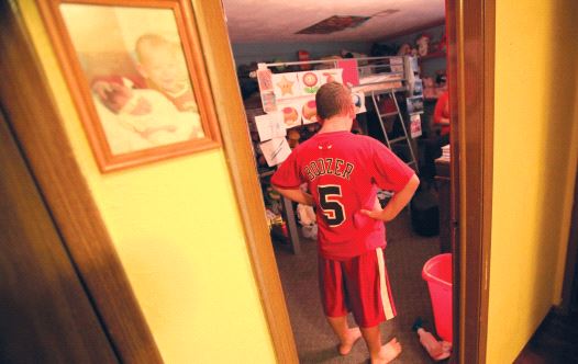 A boy with autism stands in his room