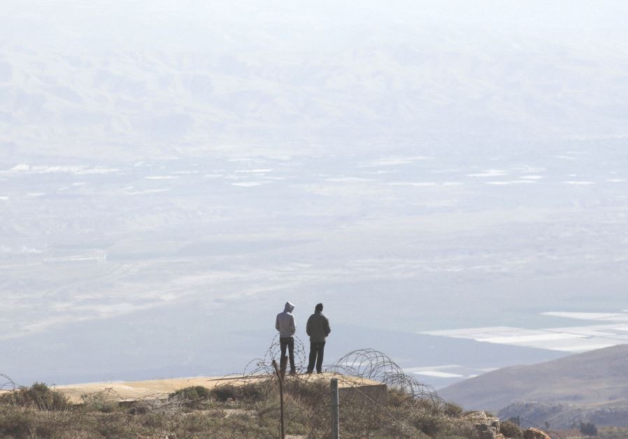 TWO SETTLERS stand atop a ridge in the West Bank.