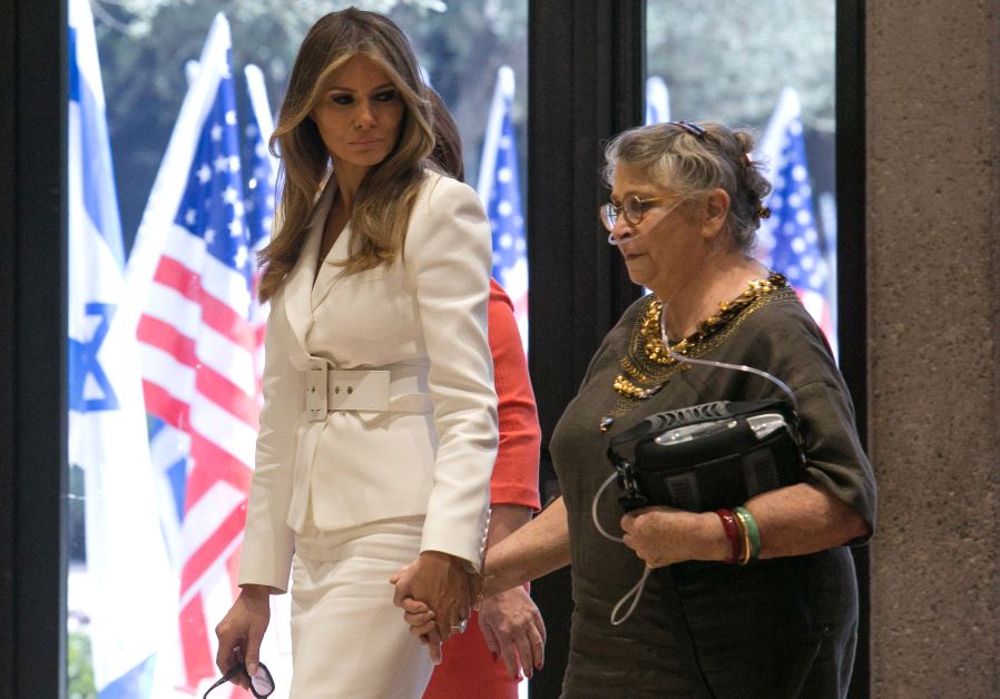 US first lady Melania Trump (L) holds the hand of Nechama Reuven, wife of Israeli president Reuven Rivlin, as they walk near American flags at Rivlin's residence in Jerusalem May 22, 2017. (photo credit: REUTERS) 