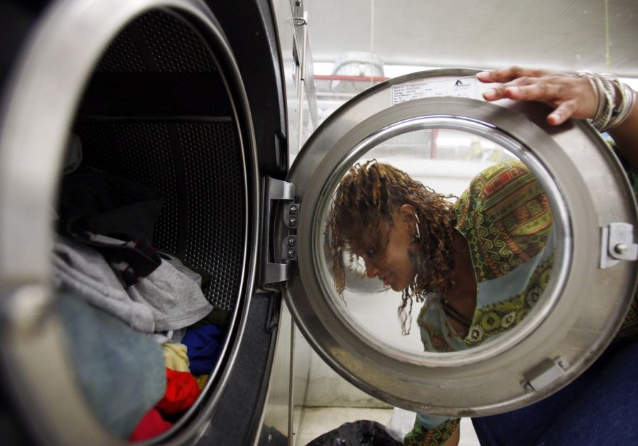 A woman loads laundry into the washing machine at a laundromat in Cambridge, Massachusetts July 8, 2009.