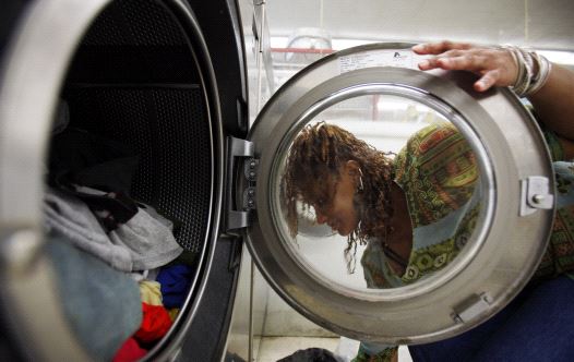 A woman loads laundry into the washing machine at a laundromat in Cambridge, Massachusetts July 8, 2009. (credit: REUTERS/BRIAN SNYDER)
