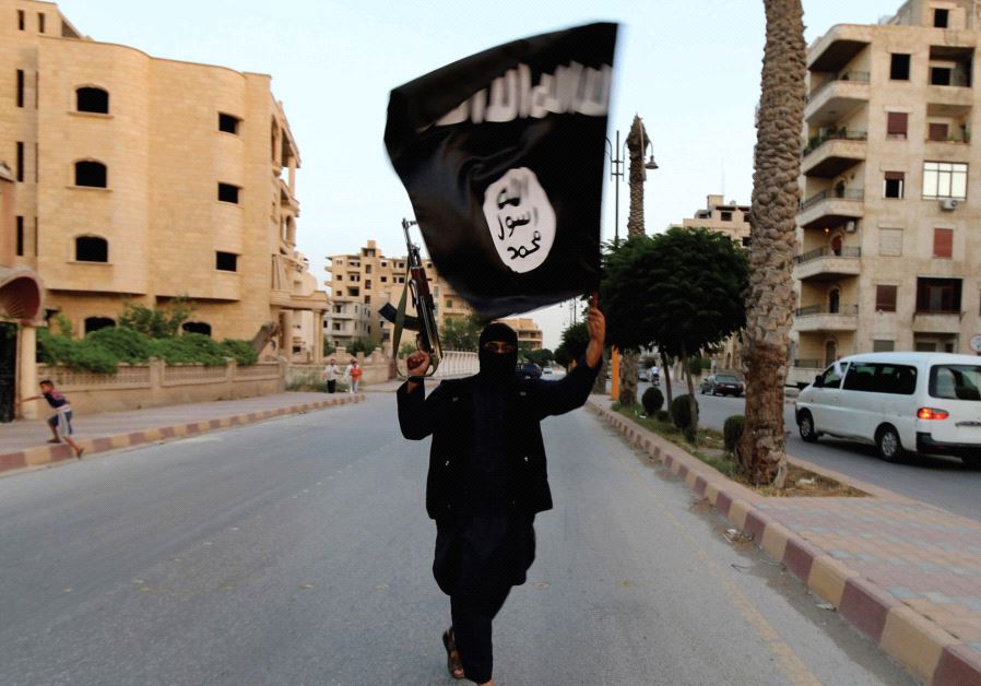 A MEMBER of ISIS waves the group’s flag in Raqqa (credit: REUTERS)