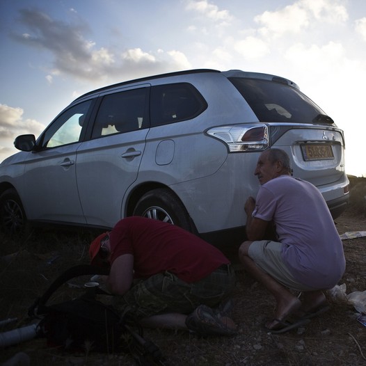 Some Israelis take cover as others look on as sirens indicating rockets being fired to the area are heard on a lookout hill near Sderot, opposite the northern Gaza Strip.