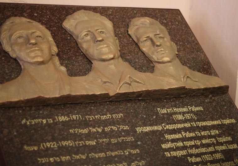 A memorial tablet carrying the bronze image of Nechemia Rabin flanked by his two children, Yitzhak and Rachel