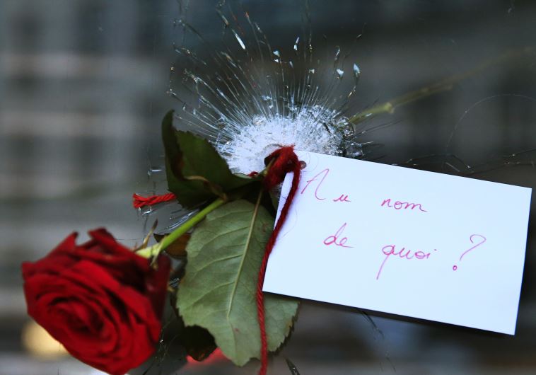 A rose placed in a bullet hole in a restaurant window the day after a series of deadly attacks in Paris, November 14, 2015. The note reads "In the Name of What?"