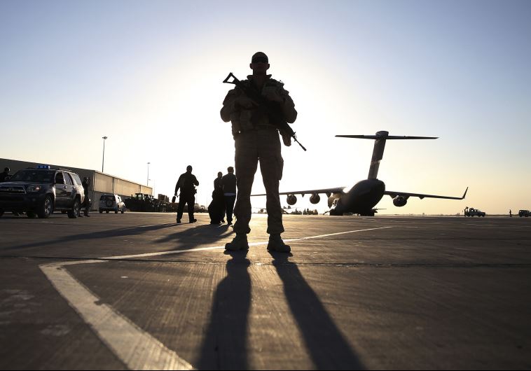 A soldier stands guard near a C-17 Globemaster III aircraft sitting on the tarmac at Kandahar Air Base in Afghanistan on December 8, 2013