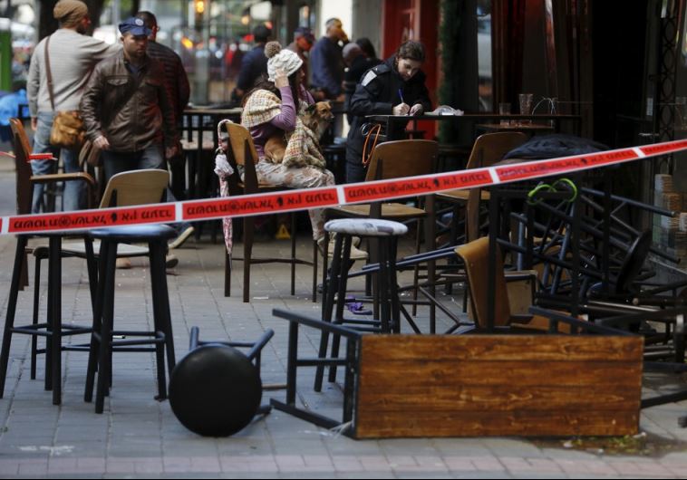 A woman sits with her dog after being questioned by police at the scene of a shooting incident in Tel Aviv