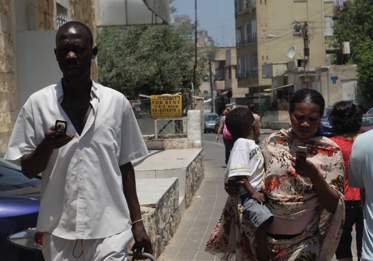 A Sudanese woman checks her cellphones as they walk along a street in Tel Aviv