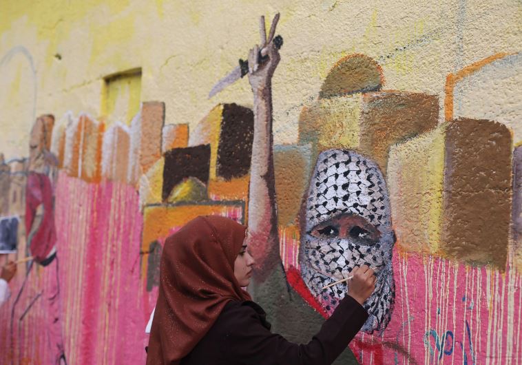 A PALESTINIAN woman paints a mural in support of Palestinians committing stabbing attacks against Israelis, in the southern Gaza Strip in November