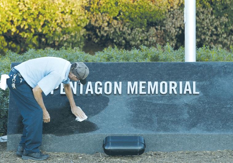 A MAINTENANCE worker wipes off early morning dew at the Pentagon 9/11 Memorial in Washington DC. (