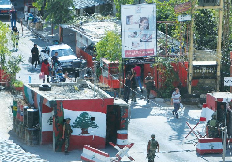 PEOPLE WALK THROUGH a Lebanese Army checkpoint at an entrance to the Ain al-Hilweh Palestinian refugee camp near Sidon in September.