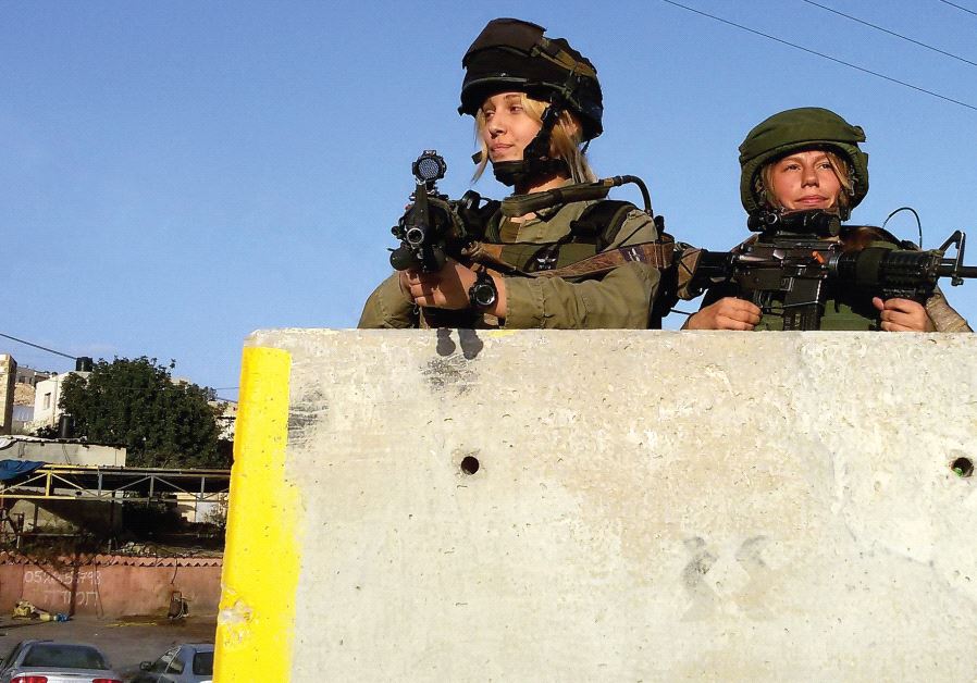 Two female soldiers from Masada Company take up defensive positions during a recent patrol near the West Bank village of Hizma