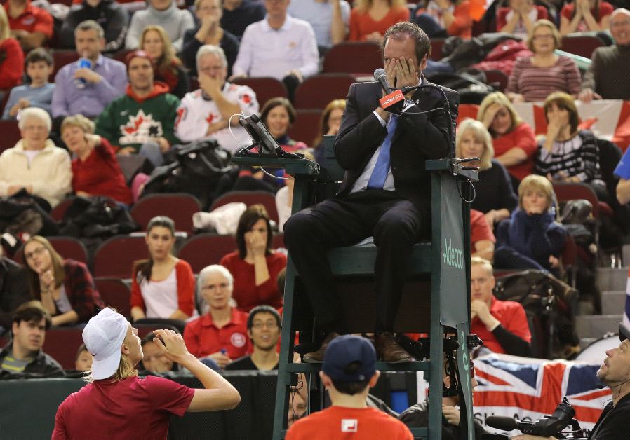 Denis Shapovalov (botton left) of Canada reacts after accidentaly hitting the head umpire Arnaud Gabas from France, during third set action against Kyle Edmund of Great Briatain on the third day of Davis Cup first round between Canada and Great Britain at TD Place in Ottawa, Ontario, February 5, 201