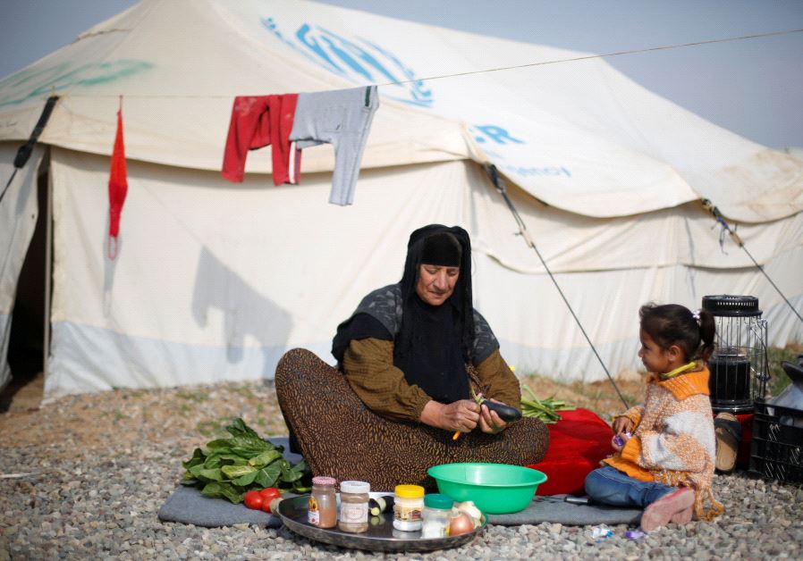 A displaced woman who fled the Islamic State stronghold of Mosul with her family makes the food in front of her tent at Hassan Sham camp, east of Mosul, Iraq