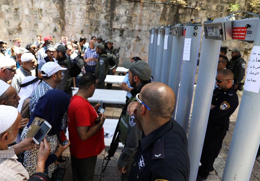 Palestinians stand in front of Israeli police officers and newly installed metal detectors at an entrance to the  Temple Mount, in Jerusalem's Old City July 16, 2017.