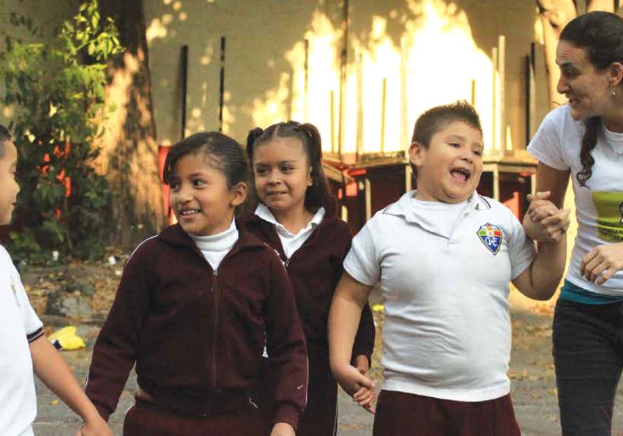 E4S children hold hands with its founder and president, Dina Auron.